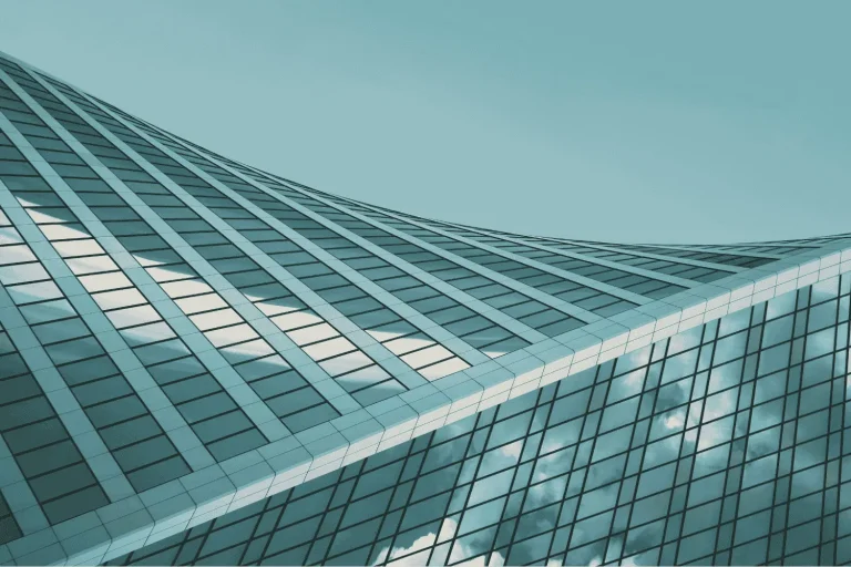 Three large industrial ventilation fans mounted on a rooftop with residential buildings in the background.