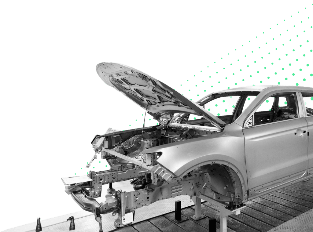 Black and white image of a partially assembled car frame on a production line, with the hood open and internal components exposed.