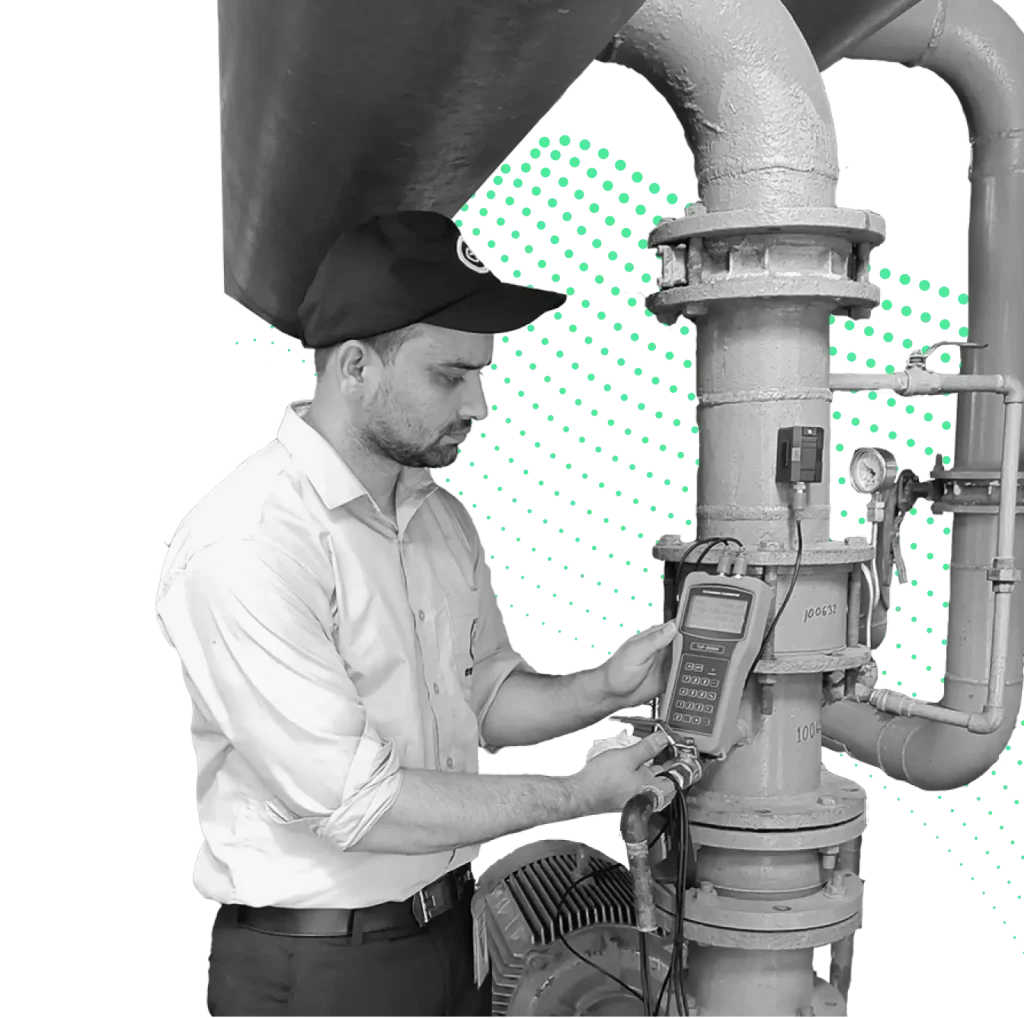 A technician wearing a cap and uniform conducting an inspection on an industrial pipeline using a handheld digital meter, with a dotted green pattern in the background.